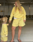 Two people in matching yellow outfits standing in a large indoor space with high ceilings.