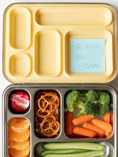 School lunch packed in a kids stainless steel bento box with a handwritten note from Dad tucked into the lid